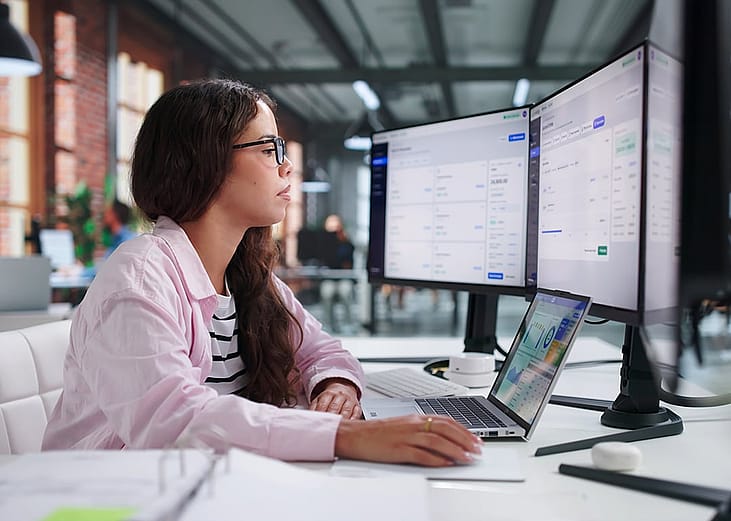 An accountant checking financial reports in a multi-screen computer.