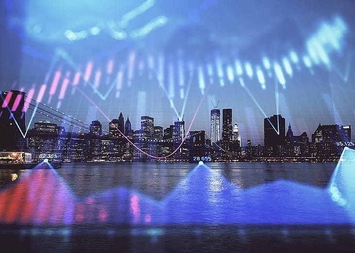 Financial graphs overlaid on a view of the city skyline at night.