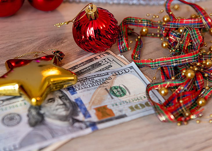 US dollar bills and Christmas decorations on a desk.