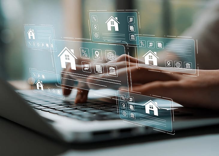 A person using a laptop with a digital holographic interface displaying real estate, housing, and financial icons.