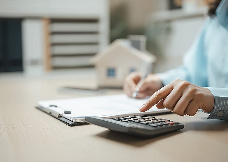 A property professional working on a document and using a calculator.