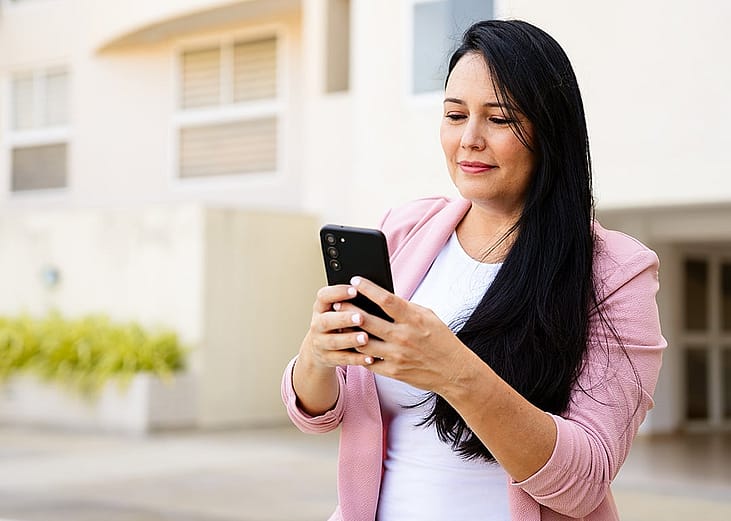 A realtor checking her smartphone outdoors for property messages or other listings from clients.
