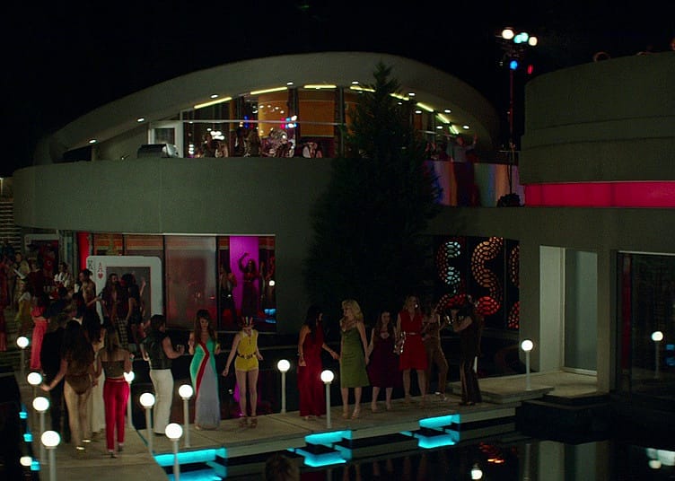 A modern mansion with a party going on by the pool.