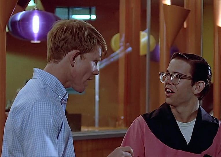 Two boys talk in front of a colorful diner.