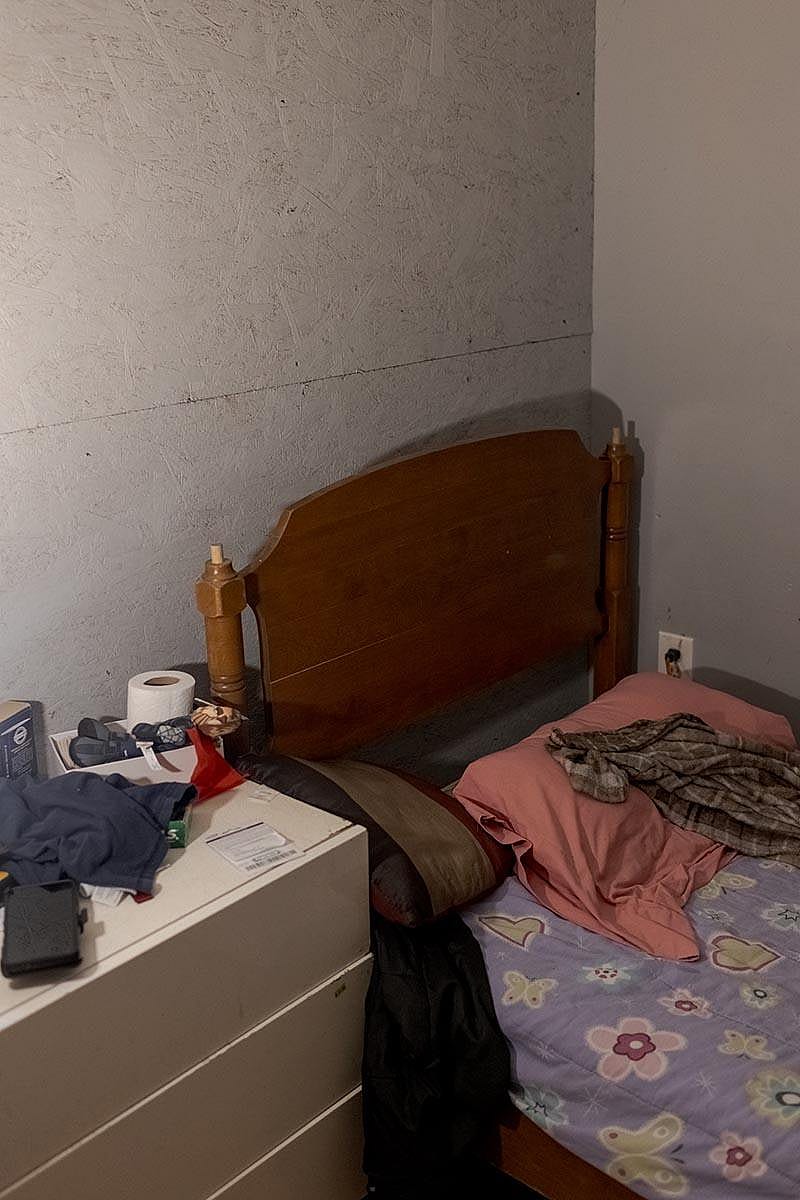 A farm worker’s bedroom, which barely accommodates a small twin bed, inside a dairy barn.