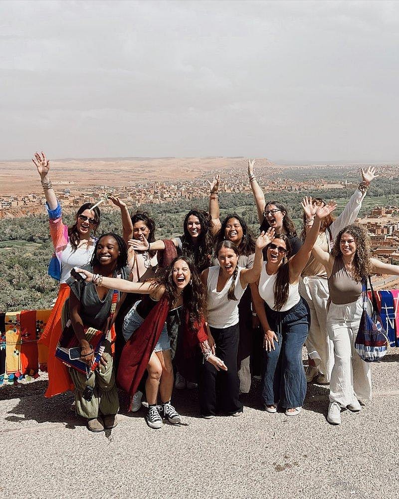 Young tourists posing for a photo with the desert landscape of Morocco as their backdrop.