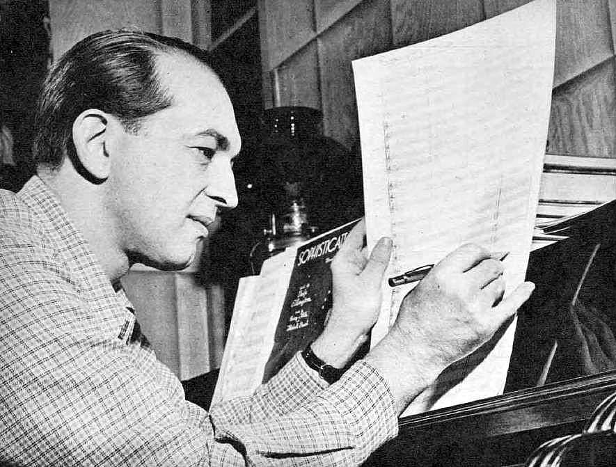Bandleader Percy Faith makes notes on sheet music