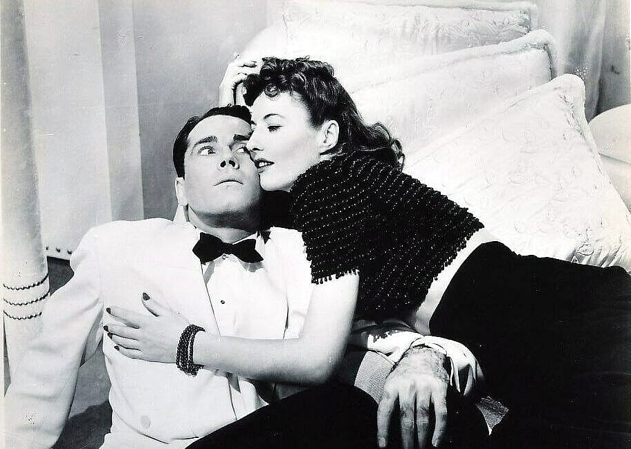 A woman leaning over a chair pressed againsta a man's face.