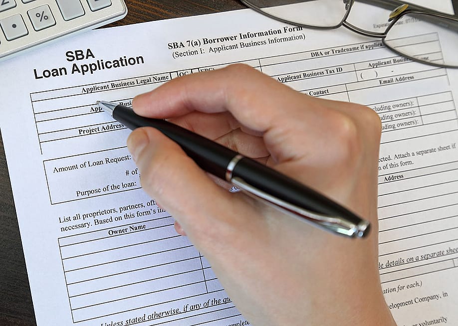 Person filling out paper SBA loan application form by hand. — Kilmer Media // Shutterstock