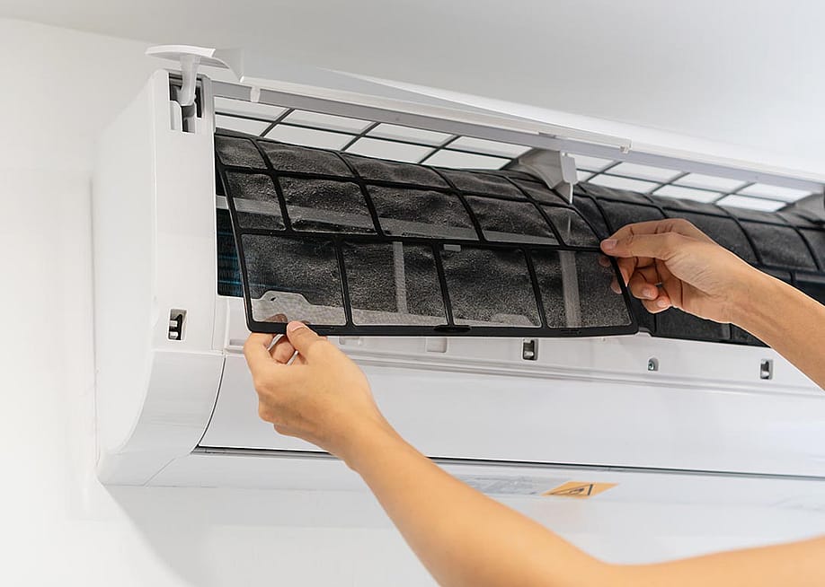 Person pulling out a dirty air conditioner filter from a mini-split unit. — Opat Suvi // Shutterstock