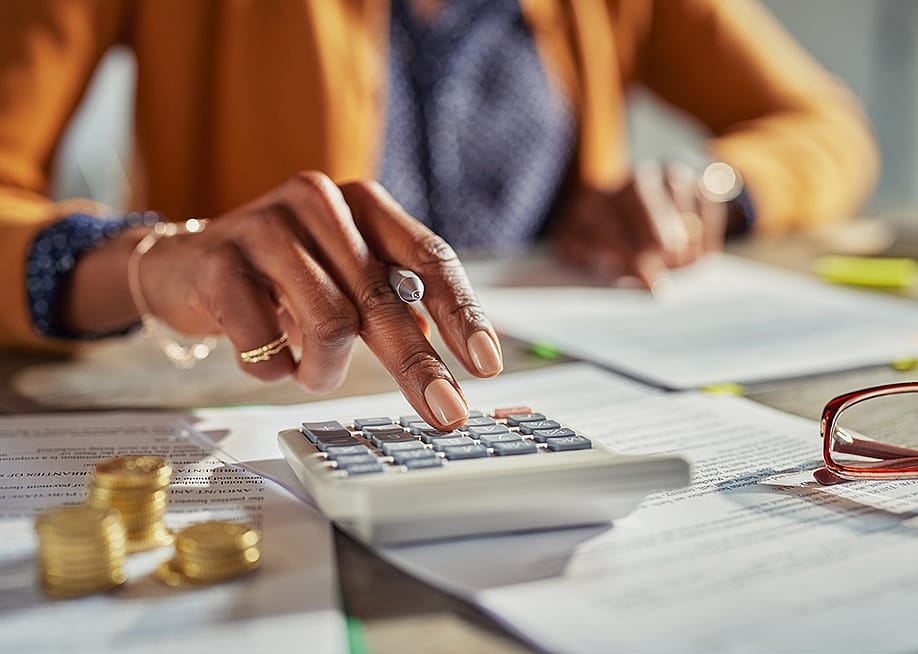 Tax professional using a calculator while reviewing finance documents. — Rido // Shutterstock