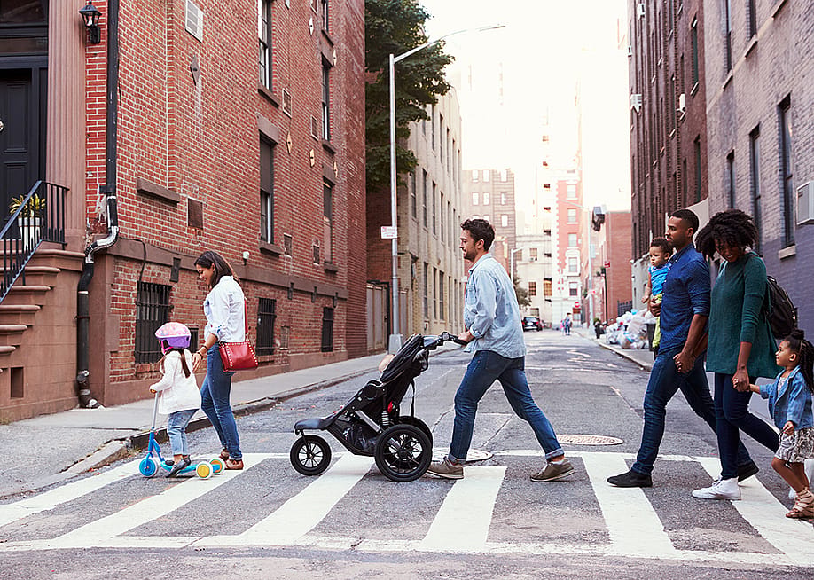Two families crossing a road along an apartment neighborhood. — Monkey Business Images // Shutterstock
