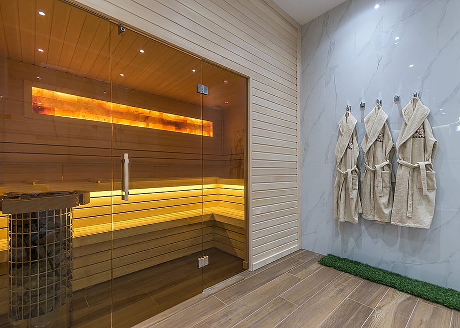 A modern home sauna with bathrobes hanging on its wall. — Alhim // Shutterstock
