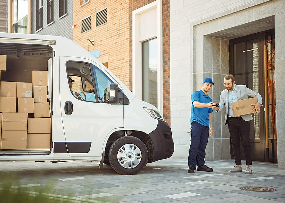 Delivery man gives postal package to its consignee in a business address. — Gorodenkoff // Shutterstock