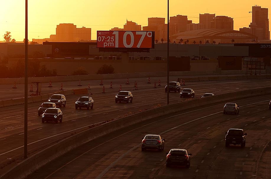 A billboard shows the current temperature over 100 degrees on June 05, 2024 in Phoenix, Arizona as drivers travel on the freeway in the foreground in the shadow of the setting sun. — Justin Sullivan // Getty Images