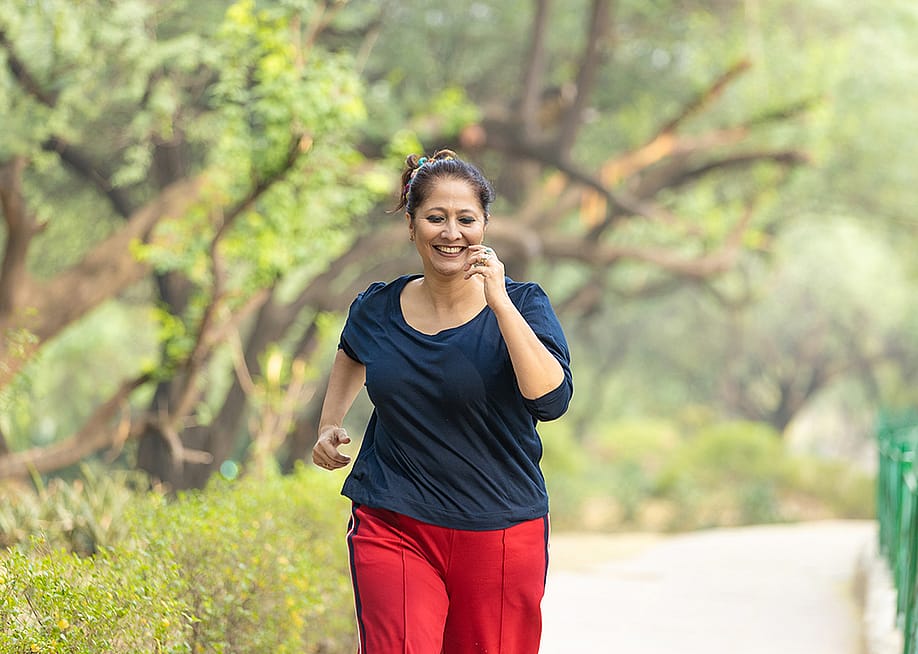 A middle-aged woman jogging at the park. — PRASANNAPIX // Shutterstock