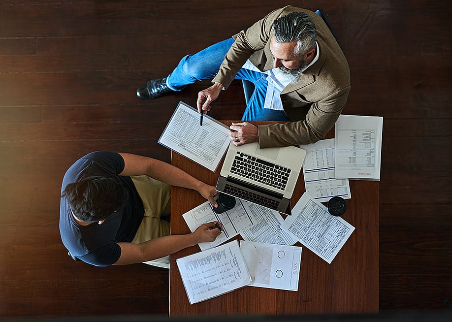 Two businessmen discussing strategy with accounting documents on their table. — PeopleImages.com - Yuri A // Shutterstock