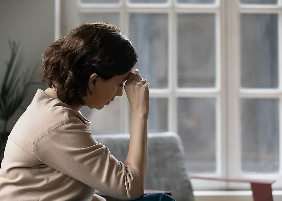A middle aged woman sits in a worried state. — fizkes // Shutterstock