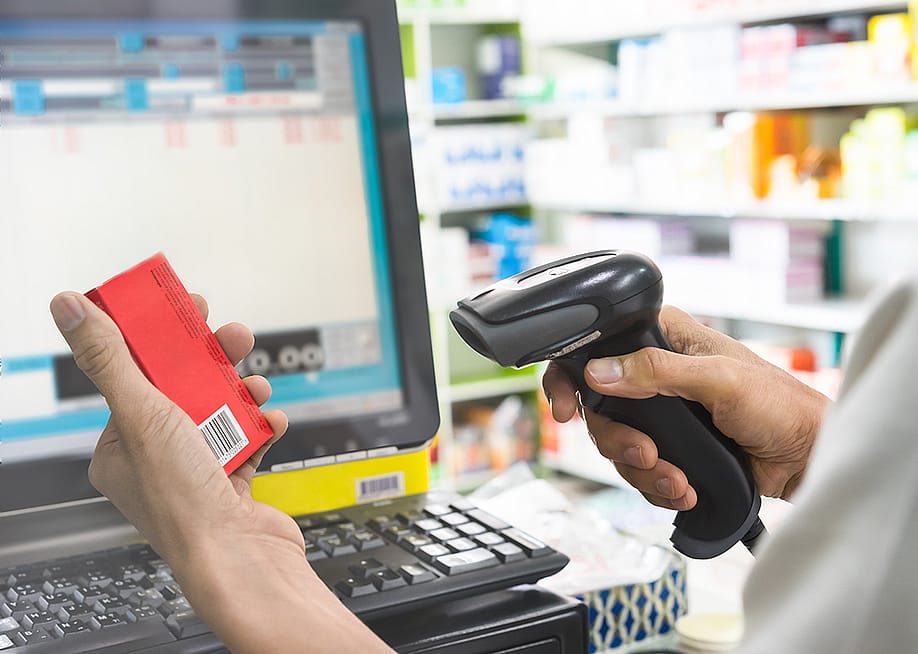 Pharmacist scanning price on a box of medicine. — Studio217 // Shutterstock