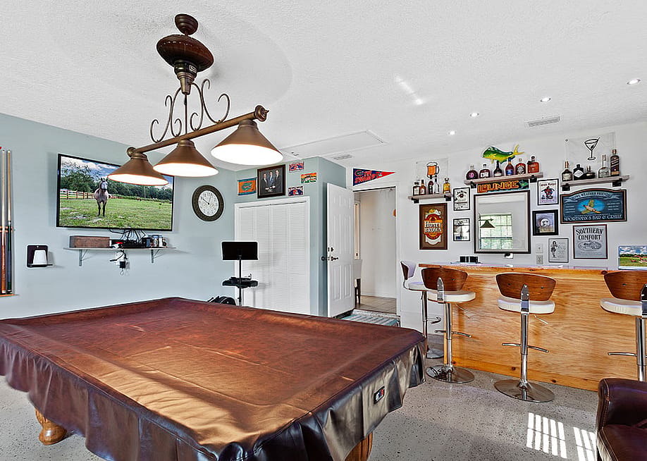 A pool table covered in leather in a game room. — Pipas Imagery // Shutterstock