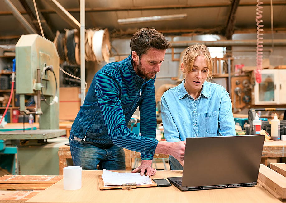 A pair of woodwork business owners reviewing reports in a laptop. — Monkey Business Images // Shutterstock