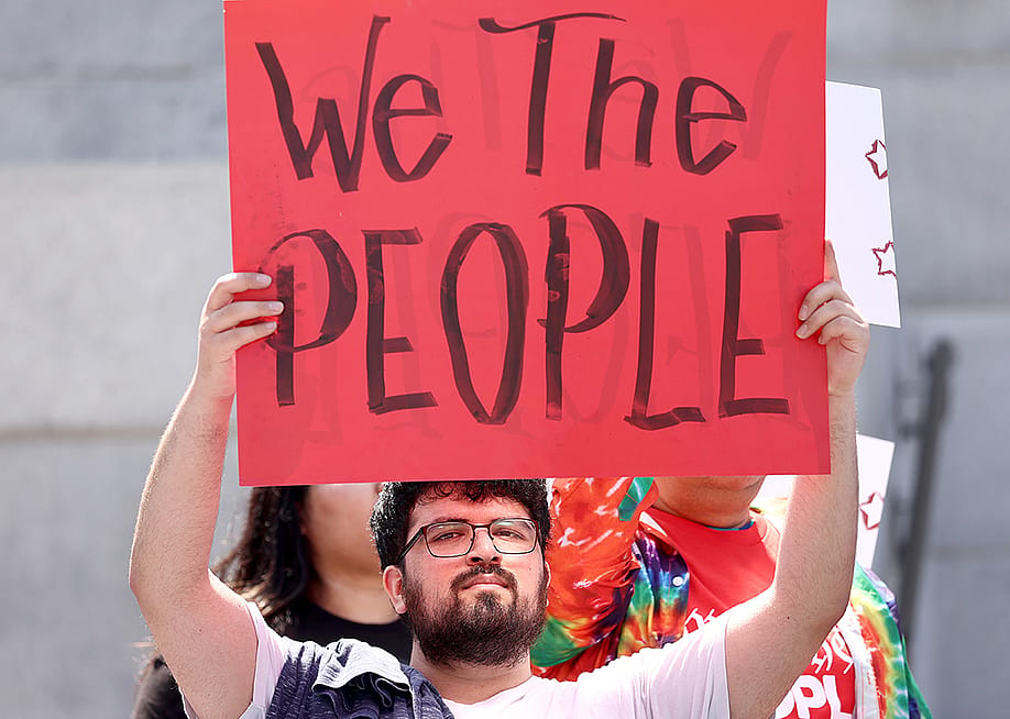 Demonstrators hold signs during the We The People March in Los Angeles, California. — Mario Tama // Getty Images