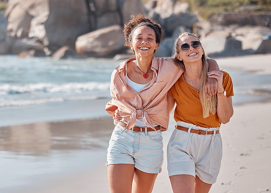 A happy lesbian couple walking on the beach. — PeopleImages.com - Yuri A // Shutterstock