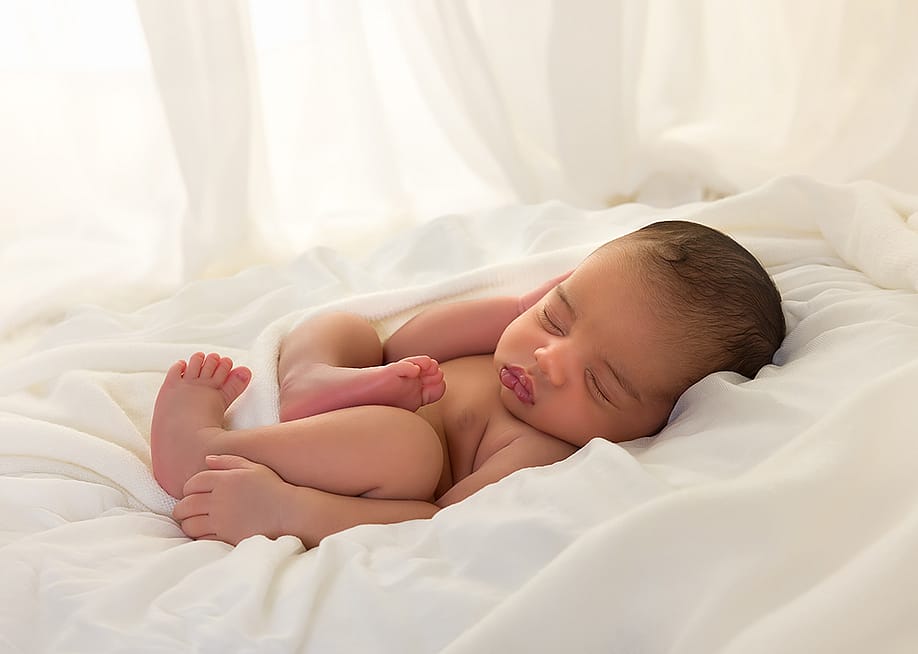 Newborn baby sleeping in bed. — Anneka // Shutterstock