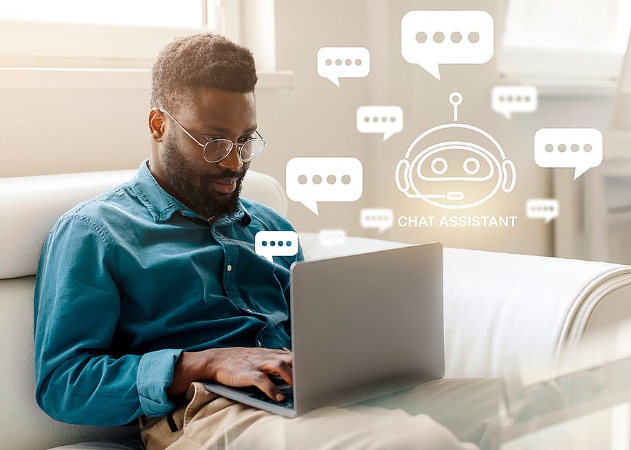 Man sitting on the couch at home using a laptop to chat with an AI bot. — Prostock-studio // Shutterstock