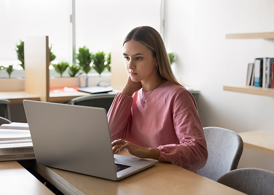 Young college student using a laptop to browse through finances. — fizkes // Shutterstock