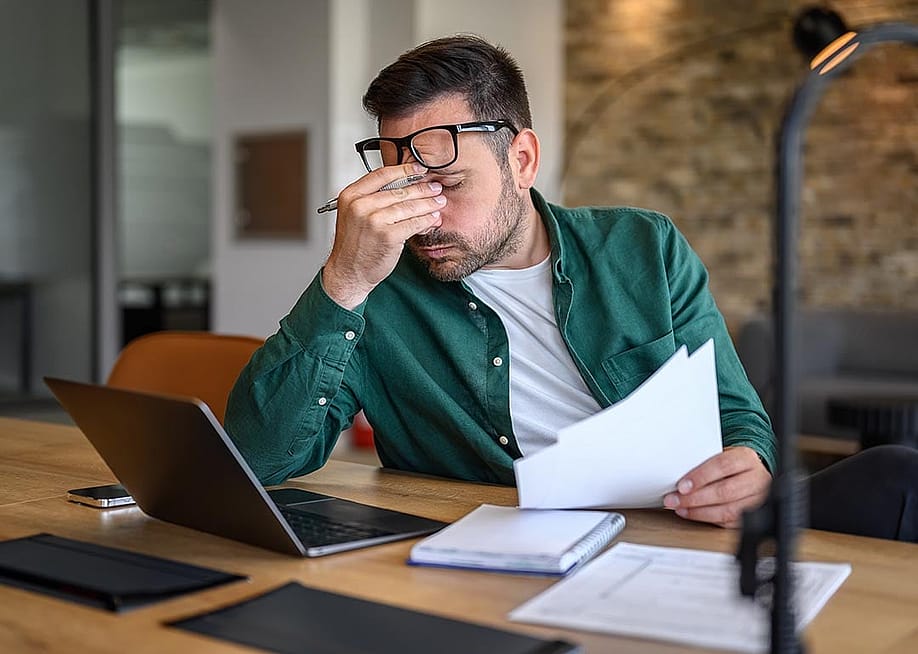 Anxious landlord rubbing eyes while looking at documents. — Moon Safari // Shutterstock