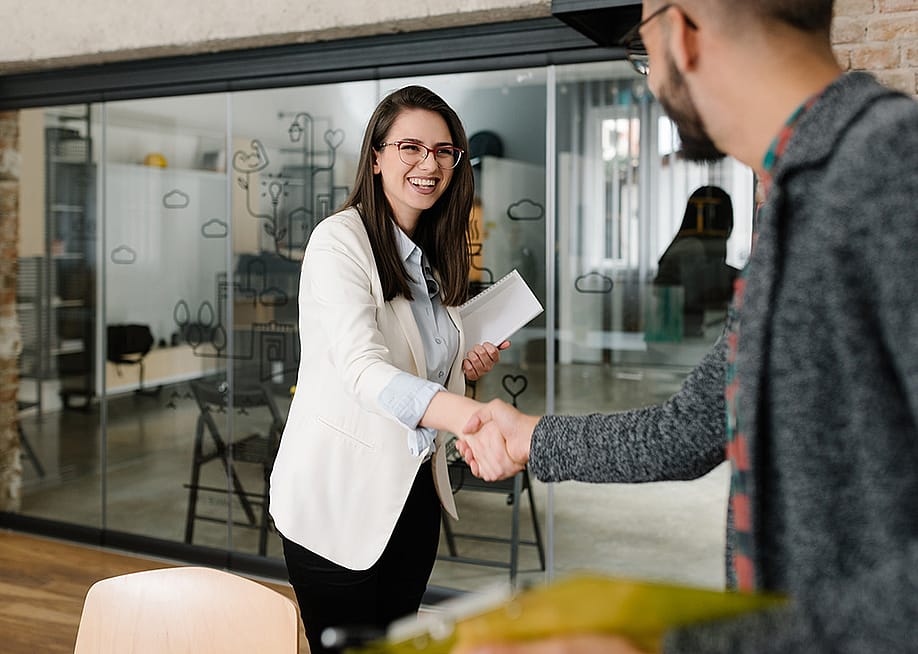 Businesswoman greeting a finance professional with a firm handshake. — djrandco // Shutterstock