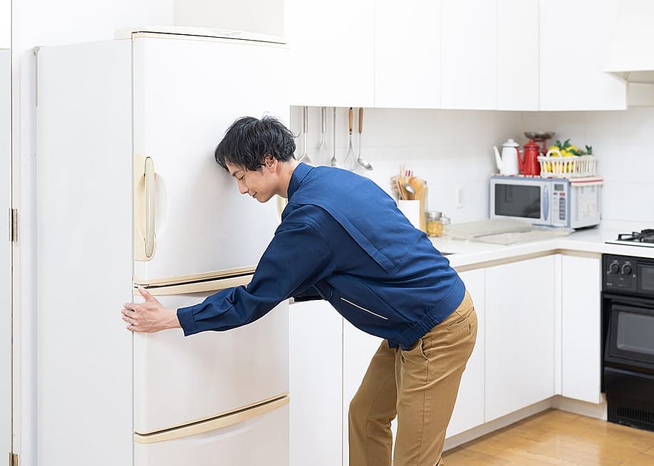 Man fixing the placement of his fridge in the kitchen. — polkadot_photo // Shutterstock