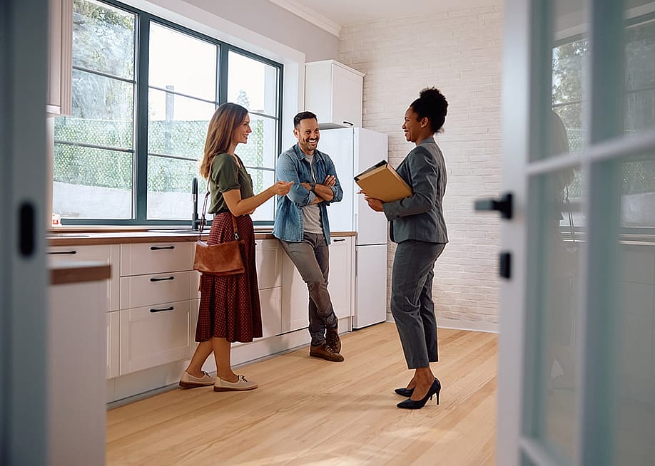 A couple talking with a real estate agent. — Drazen Zigic // Shutterstock