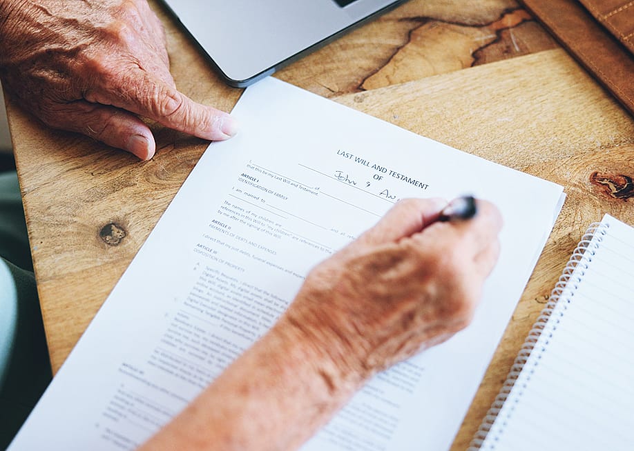 A senior person signing a last will and testament document. — PeopleImages.com - Yuri A // Shutterstock
