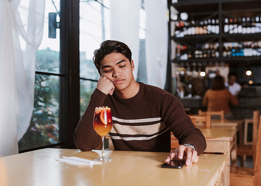 Young man who was ghosted by his date sits alone disappointed in a restaurant. — MDV Edwards // Shutterstock