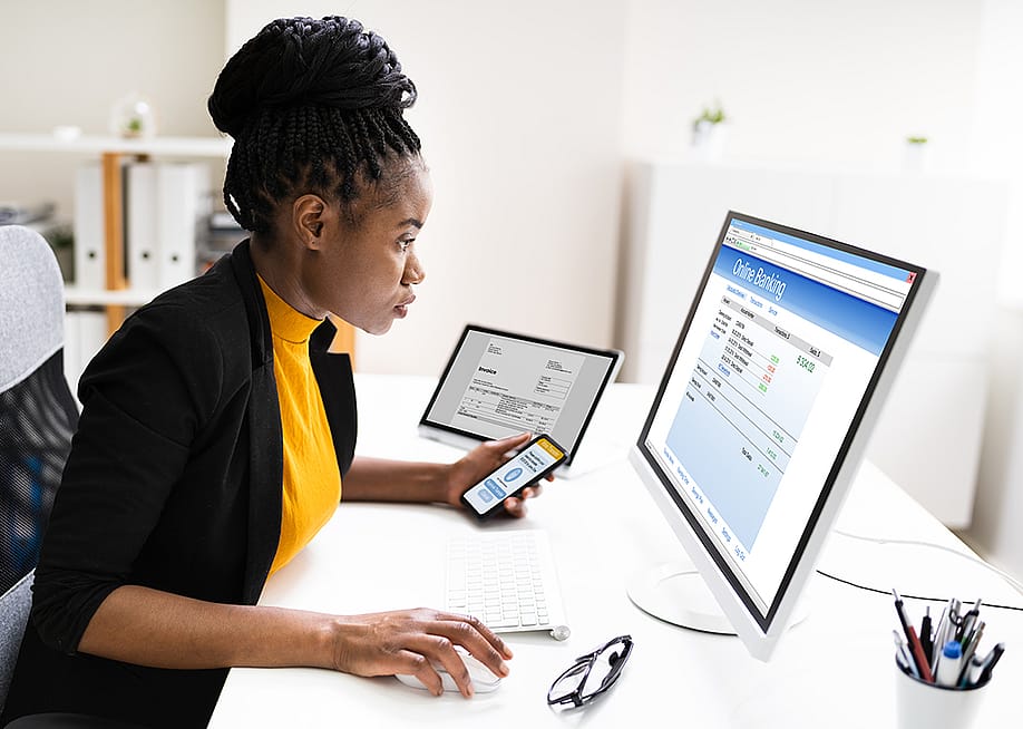 Woman using a phone and computer to use online banking. — Andrey_Popov // Shutterstock