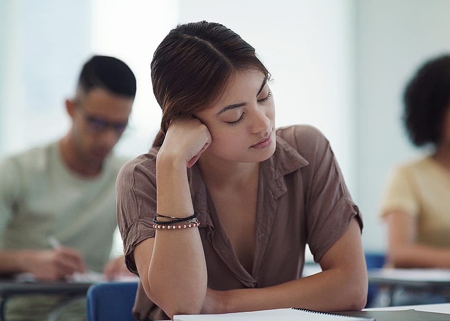 Young female college student feeling burned out in a classroom. — PeopleImages.com - Yuri A // Shutterstock