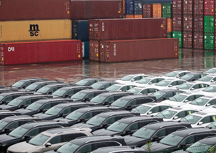 Rows of imported cars lined up across shipping containers. — humphery / Shutterstock
