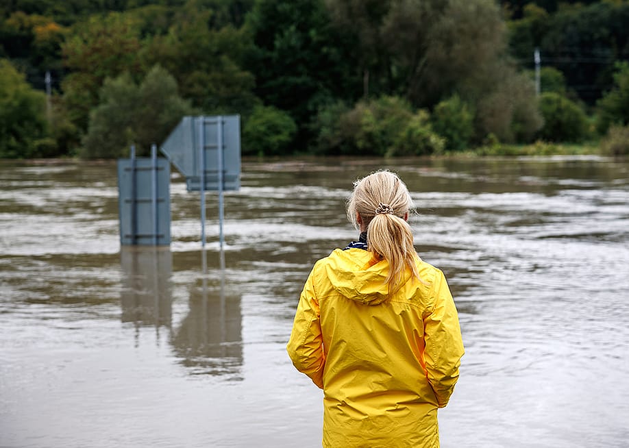 A woman in a raincoat looking over a huge flood. — encierro // Shutterstock
