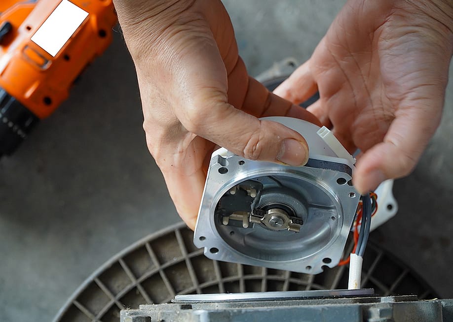 A mechanic repairing an AC servo motor. — Rito Succeed // Shutterstock