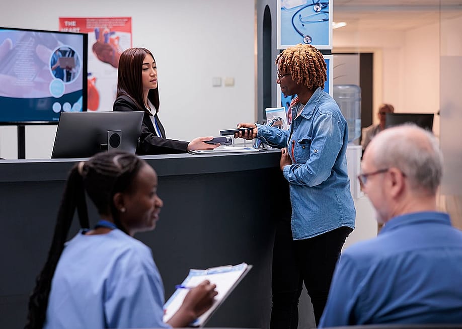 Patients and staff in a hospital reception desk area. — DC Studio // Shutterstock