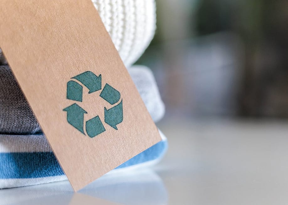 Knitted clothes with a craft tag showing the recycling symbol. — Kostikova Natalia // Shutterstock