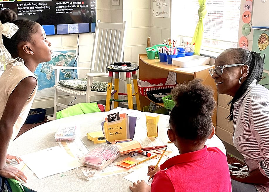 Volunteer Gae Bryant, right, works on a drawing exercise with two students in the K-2 class at The Ferguson School, a microschool that meets in an Atlanta-area church. — Linda Jacobson // The 74