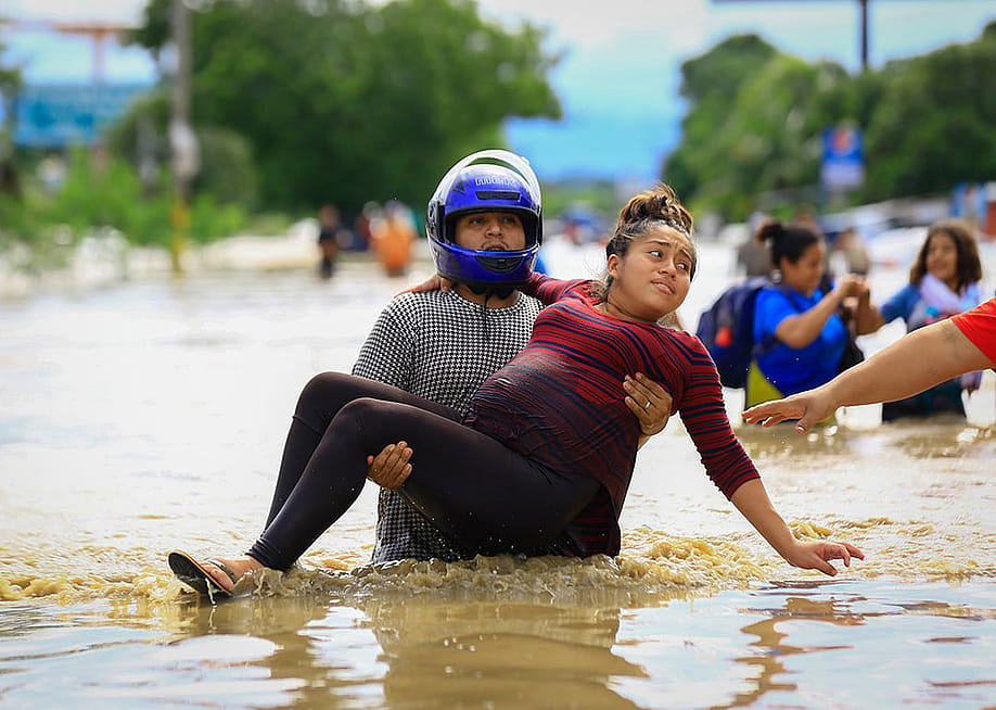 A man carries a pregnant woman through a flooded road in La Lima, Honduras after the low pressure system "Eta" caused heavy rainfall throughout the region. — picture alliance via Getty Images