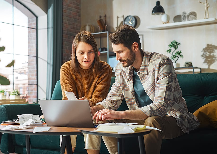 Young couple organizing bills with a laptop. — Gorodenkoff // Shutterstock