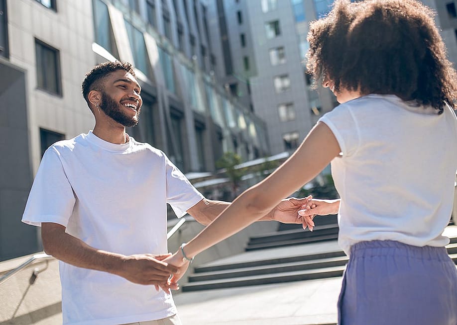 Young Black couple facing each other holding hands and playing around, dancing. — Dmytro Zinkevych // Shutterstock