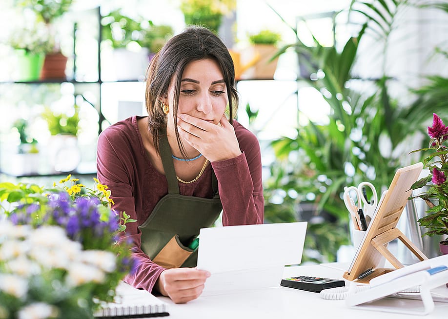 A flower shop owner carefully reviewing business documents while at the store. — Stock-Asso // Shutterstock