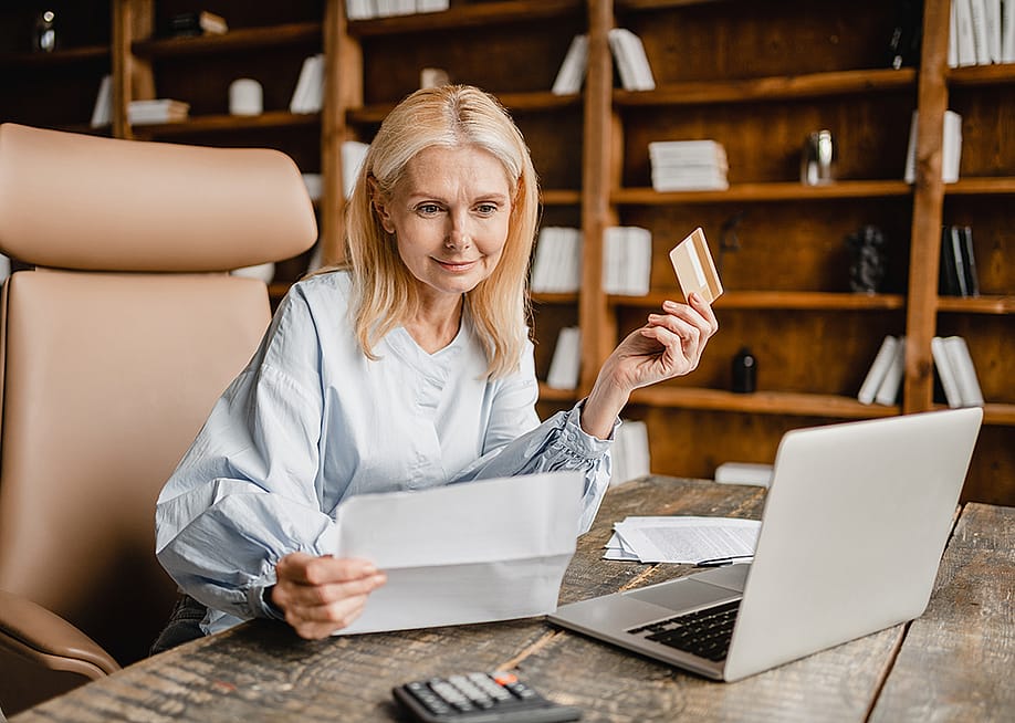 Senior businesswoman using company card to pay a bill online. — Inside Creative House // Shutterstock