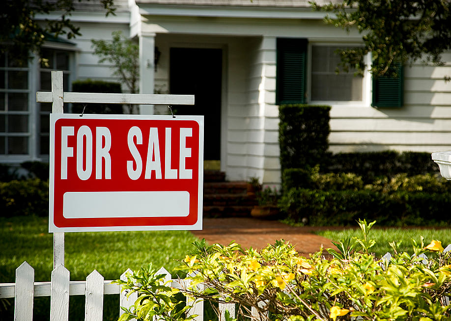 For sale sign in front of a house. — Juice Flair // Shutterstock